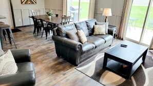 Una sala de estar con un sofá de cuero, una mesa de centro y un comedor con mesa y sillas.