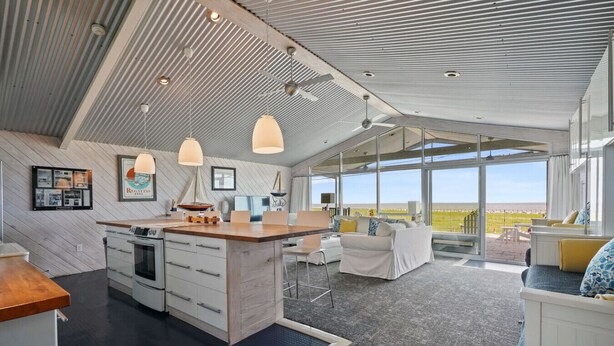 A modern kitchen with a central island, pendant lighting, and a view to the outdoors. - Relax on Lake Pontchartrain (New Orleans)