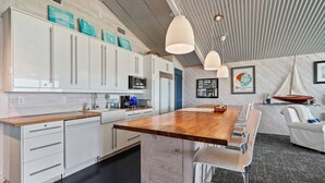 A modern kitchen with white cabinets, a wooden island, and pendant lighting. - Relax on Lake Pontchartrain (New Orleans)