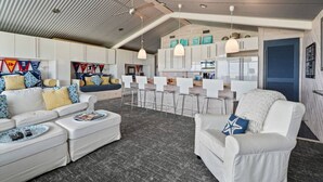 A modern interior with a high ceiling, white furniture, and a kitchen area. - Relax on Lake Pontchartrain (New Orleans)