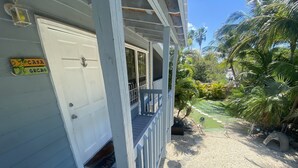 A wooden porch with a white door, a small balcony, and a sign reading "Casa Gecko".