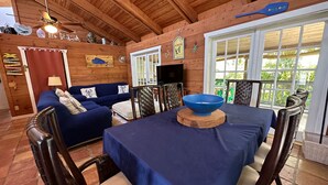 A wooden interior with a dining table, chairs, a sofa, and a ceiling fan.