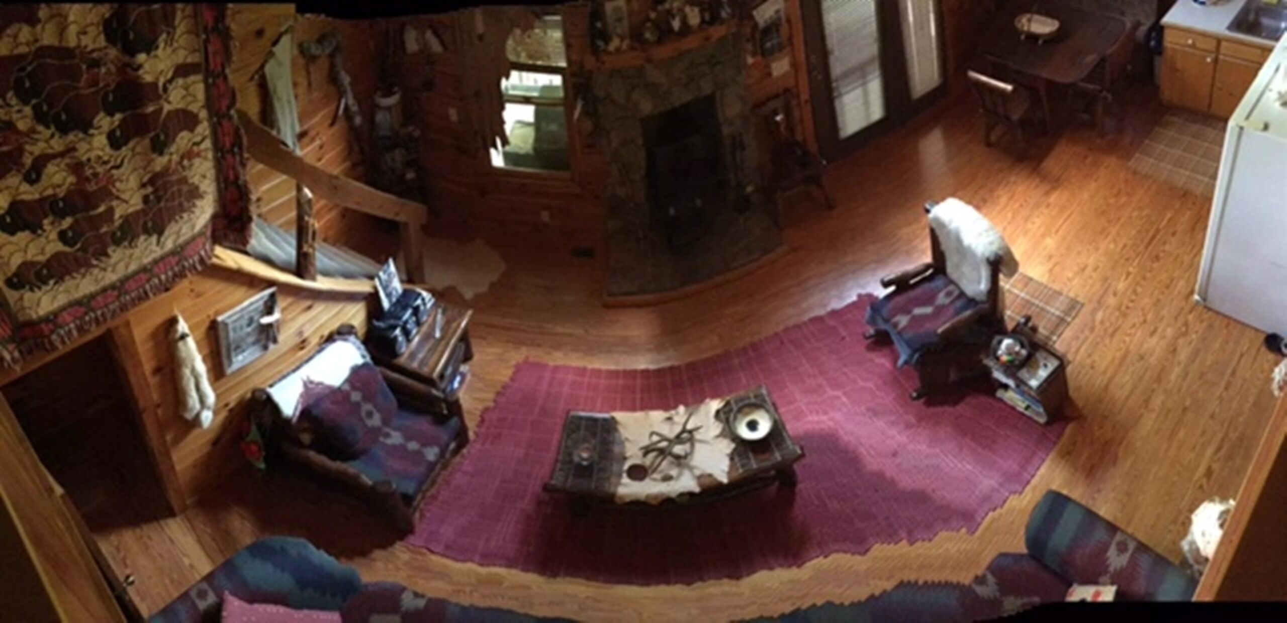 A cozy living room with a fireplace, a wooden staircase, and a dining area.