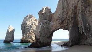 Une plage avec de grandes formations rocheuses et un ciel dégagé.