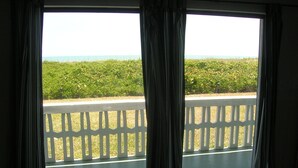 Une pièce avec vue sur un paysage verdoyant, visible à travers une fenêtre ornée de rideaux.