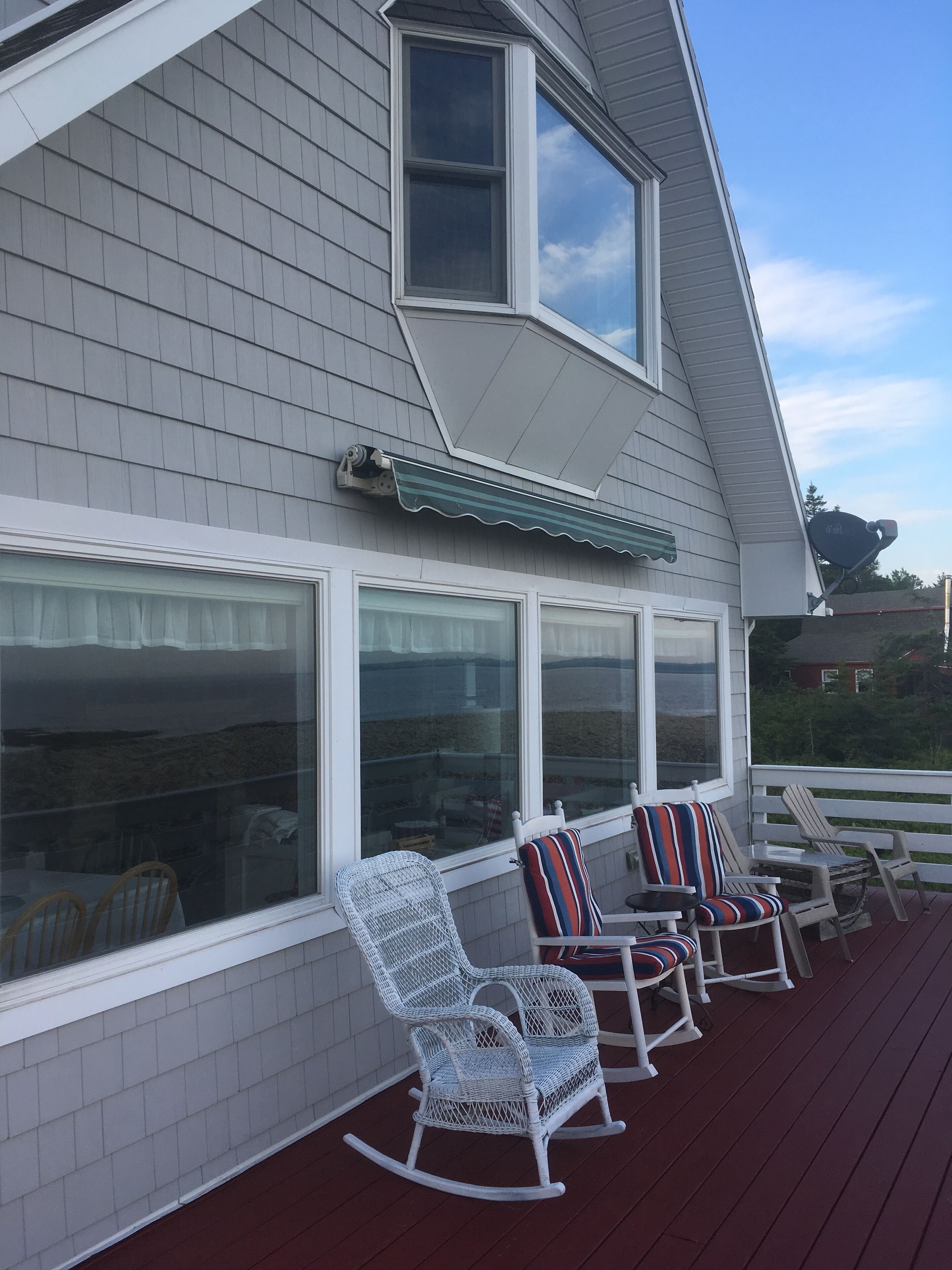 A deck with rocking chairs and a covered area.