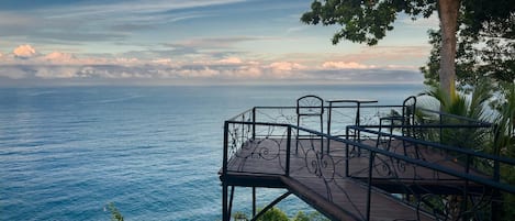 A wooden deck with metal railings overlooking a body of water.
