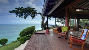 A wooden deck with a view of the ocean, a covered seating area with chairs, and a table. - 4BR Oceanfront Luxury Villa • Private Estate • Spectacular Sunsets (Dominical)
