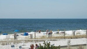 A beach with people, umbrellas, and a fence.