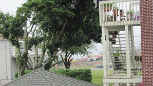 Un edificio residencial con balcón de dos pisos, patio cubierto y jardín cercado.