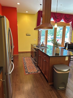 A modern kitchen with a stainless steel refrigerator, wooden cabinets, and a gas stove. - Captain's Suite - 2 Bedroom Condo in Eastsound across from the park (Eastsound)