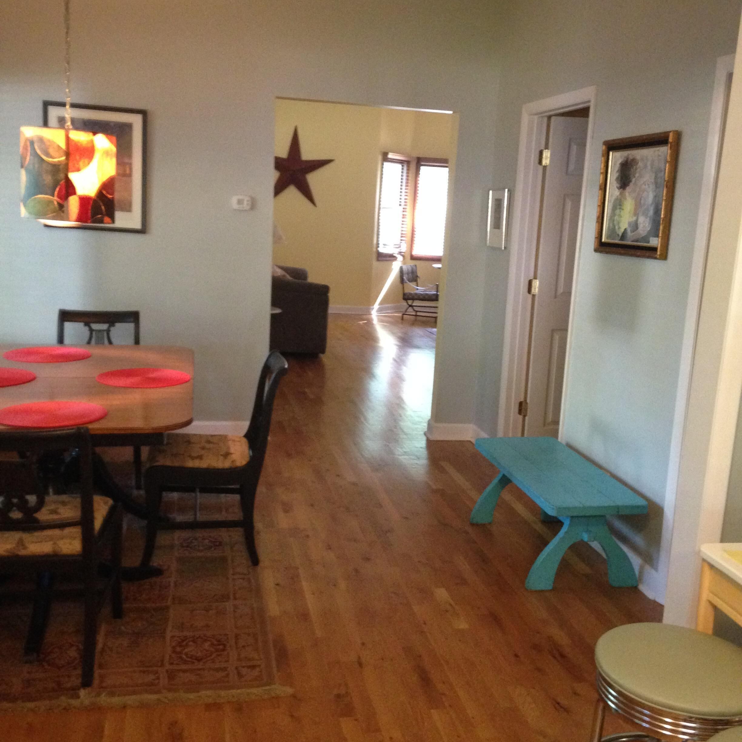 A dining area with a wooden table and chairs, a bench, and a rug.