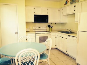 Kitchen with stove, microwave, sink, and dishwasher, plus a dining area with table and chairs.