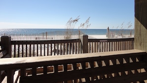 Una terraza de madera con vista a la playa y al océano.