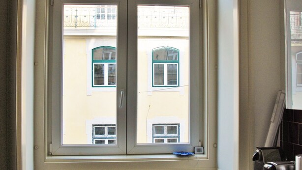 Ein Waschbereich mit Waschmaschine, Trockner und einem Fenster mit Blick auf Gebäude.