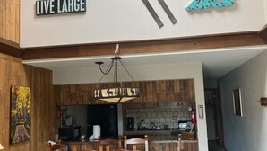 A spacious living area with a dining set, wooden accents, and a kitchen in the background. - Great family ski condo with access to all the Fraser valley has to offer (Fraser)