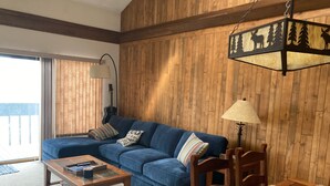 A living room with a blue sofa, wooden coffee table, and a wooden dining table with blue placemats. - Great family ski condo with access to all the Fraser valley has to offer (Fraser)