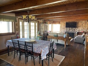 Un comedor rústico con mesa y sillas de madera, un candelabro y una pared de piedra con chimenea.