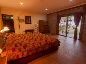 A bedroom with a large bed, a desk, a wardrobe, a fan, and a sliding glass door leading to a balcony. - COUNTRY LAKE HOUSE (Panajachel)