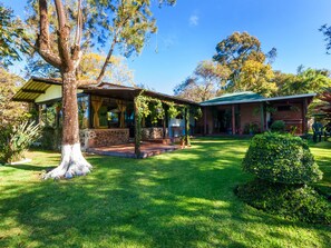 A two-story house with a stone facade, a covered porch, and a well-maintained lawn. - COUNTRY LAKE HOUSE (Panajachel)