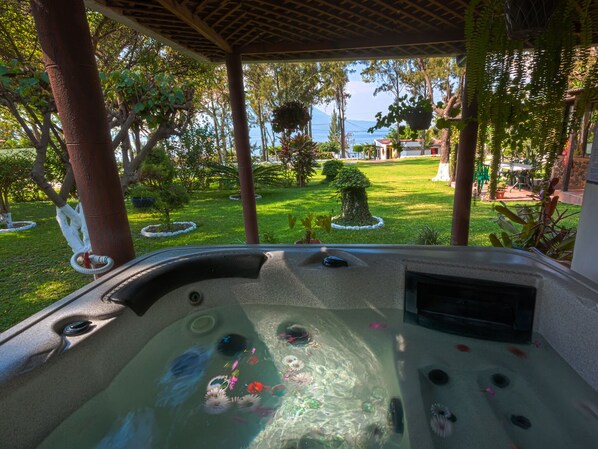 A hot tub with a view of a well-maintained garden and a body of water in the background. - COUNTRY LAKE HOUSE (Panajachel)