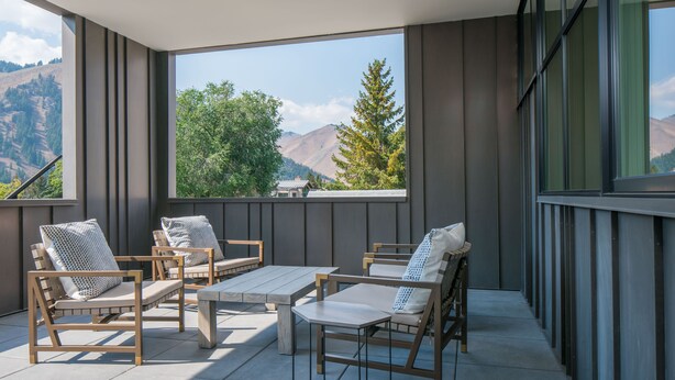Ein Balkon mit Holzmöbeln und großen Fenstern mit Blick auf die Berge.