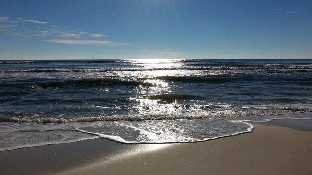 A beach with waves and a clear sky.