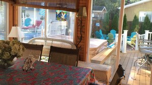 A wooden interior with a dining table, chairs, a ceiling fan, and a view through a glass door to an outdoor patio with chairs and a table. - Key West in Cape May: Hot tub open year round! Dog friendly! (Villas)