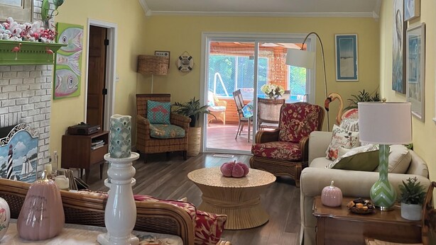 A spacious living room with a high ceiling, a ceiling fan, and a view through large windows. - Key West in Cape May: Hot tub open year round! Dog friendly! (Villas)