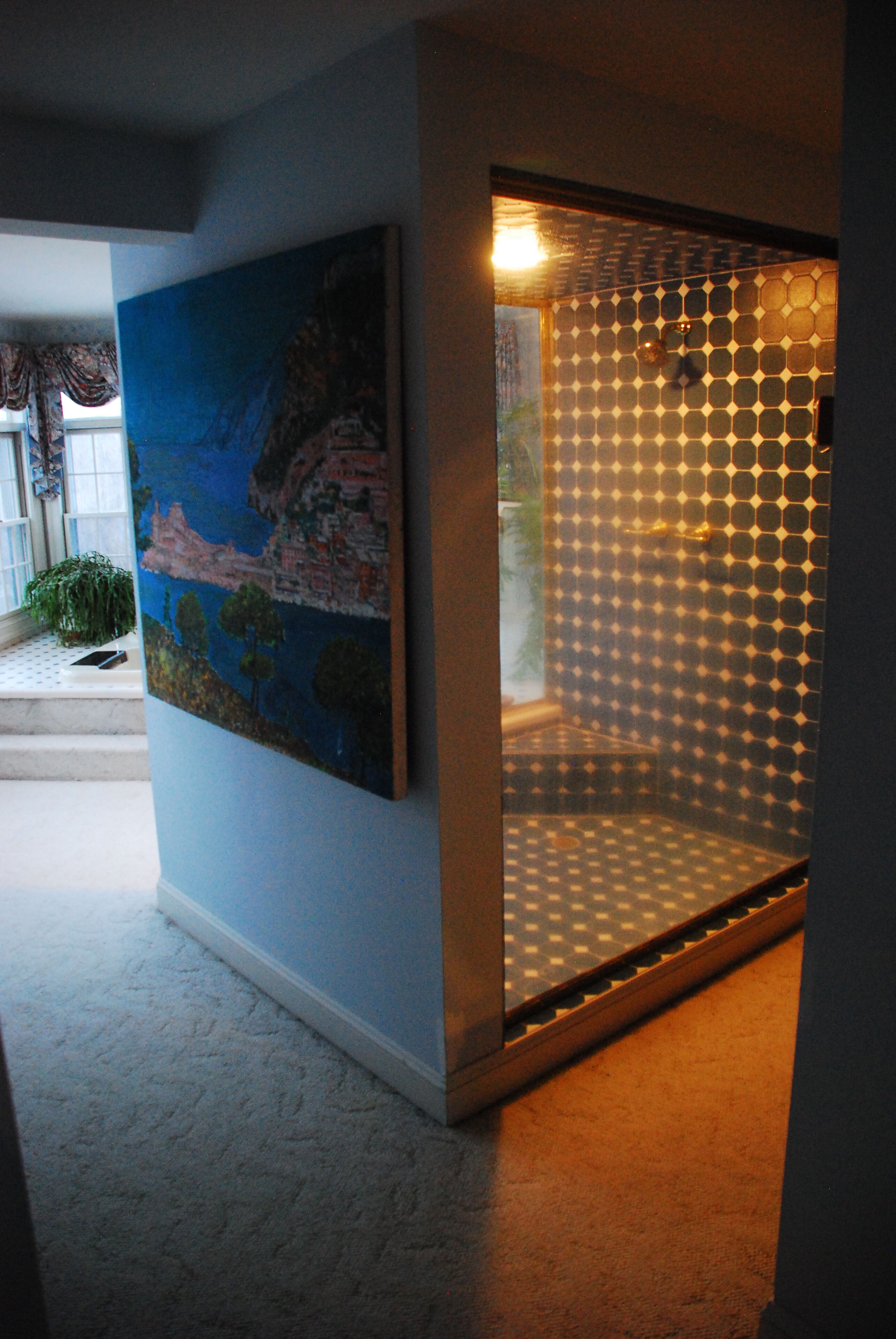 A room with a large painting on the wall, a patterned glass door, and a carpeted floor.