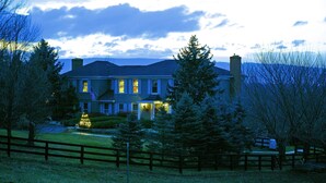 A large, two-story house with a well-maintained lawn and a wooden fence in the foreground.