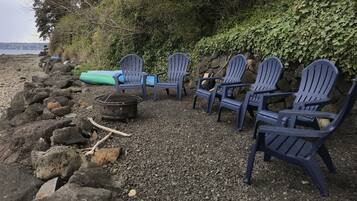 Eine Reihe Adirondack-Stühle an einem felsigen Strand mit Blick auf den Ozean.