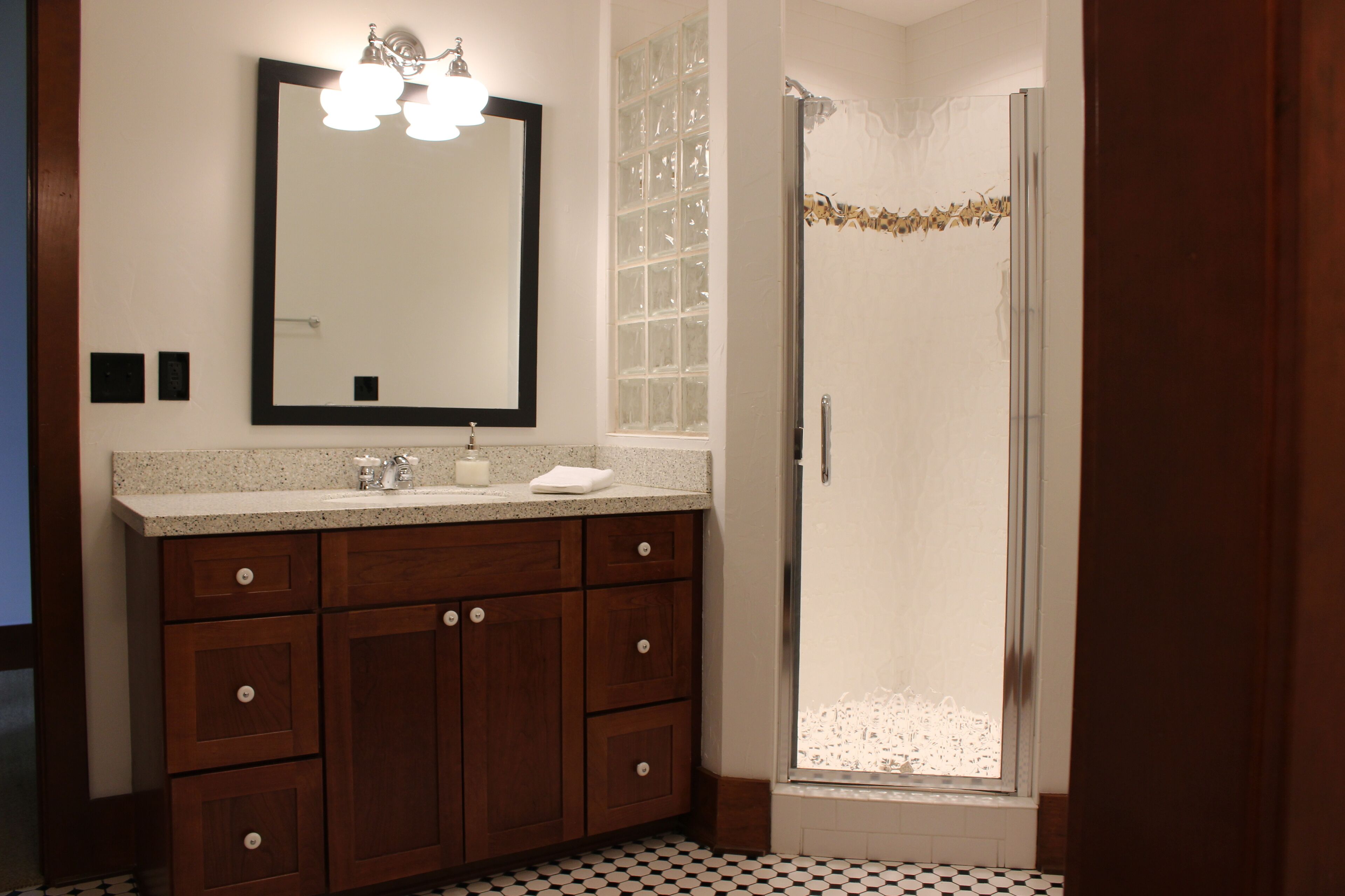 A bathroom with a wooden vanity, a large mirror, and a shower area.