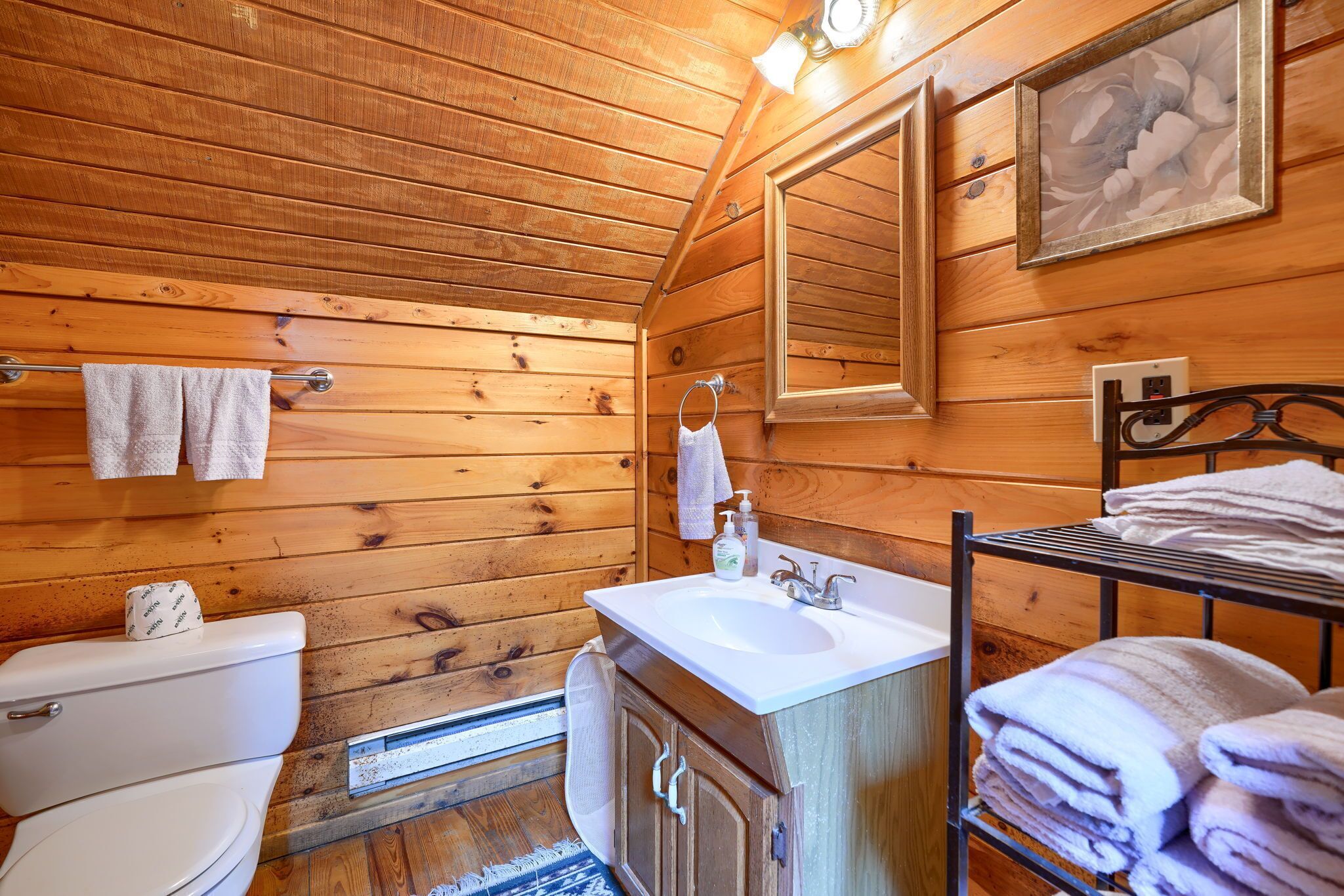 Een houten badkamer in een hutje, met toilet, wastafel en een handdoekhouder.