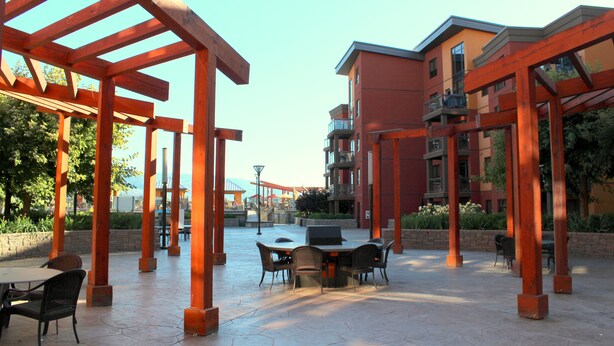 Een buitenterras met een tafel en stoelen, omgeven door houten pergola's.