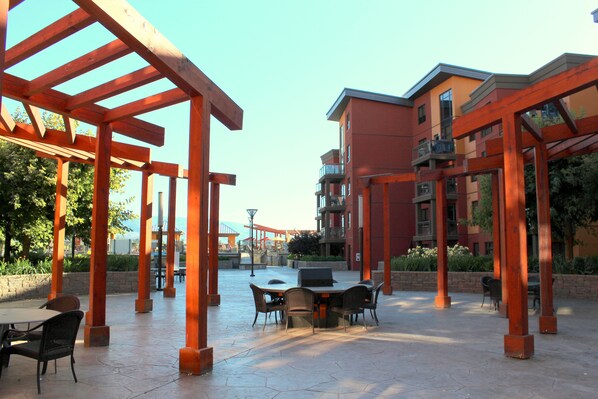 An outdoor patio area with a table and chairs, surrounded by wooden pergolas.