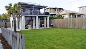A residential area with a two-story house featuring a balcony, a wooden fence, and a well-maintained lawn.