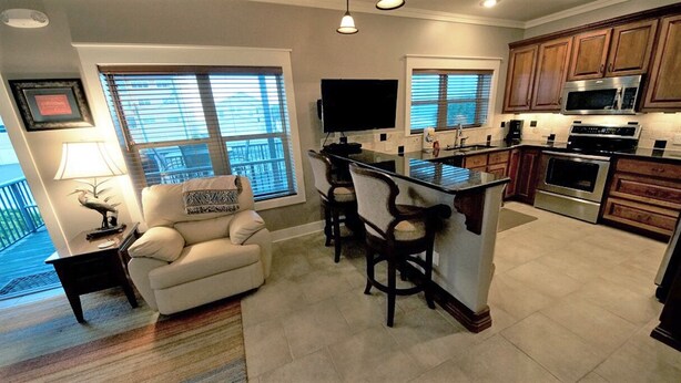 A modern kitchen with a bar area, a dining set, and a large window.