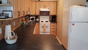 Una cocina con armarios de madera, una estufa blanca, un microondas, un lavamanos y un refrigerador.
