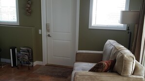 Una sala de estar con un sofá beige, una mesita pequeña con azulejos y una puerta.