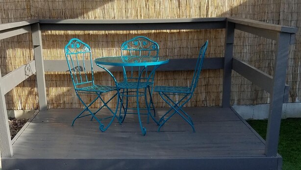 Een vuurkorf omringd door stenen zitplaatsen en een tafel met stoelen.