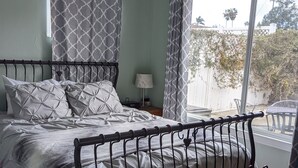 Een slaapkamer met een bed, een raam en een plafondventilator.