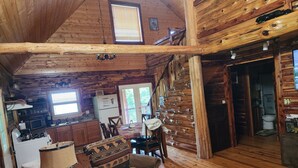 A log cabin interior with a dining area, kitchen, and a staircase leading to another level. - Dogwood Cabin, Deer Lodge Cabin Rentals is a Secluded Ozark Mountain Log Cabin.  (Jasper)