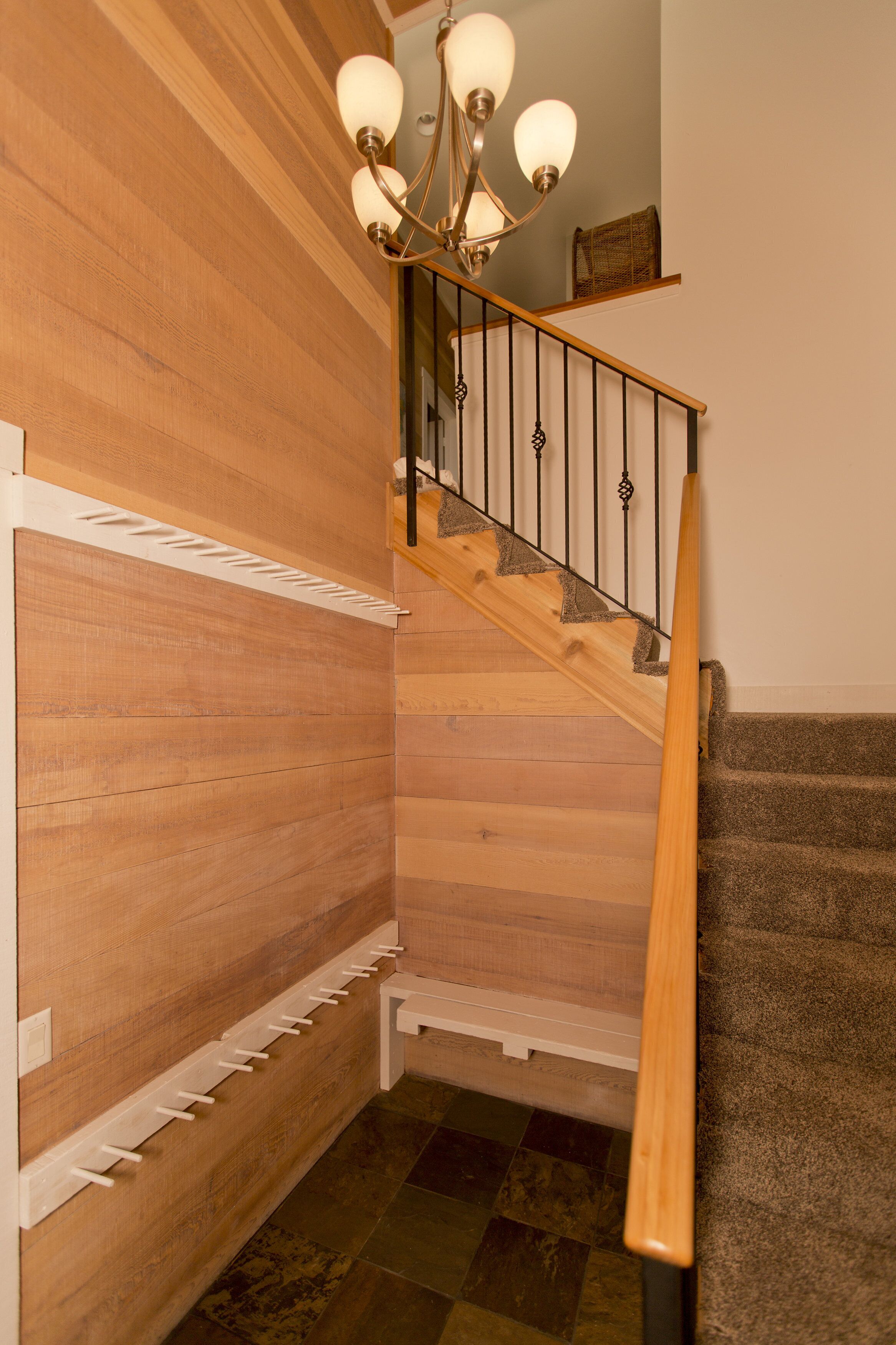 Un escalier en bois avec une rampe en métal et un lustre.