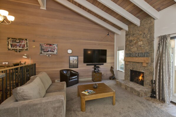 A cozy living room with a stone fireplace, a flat-screen TV, a leather sofa, and a coffee table. - Remodeled Snowcreek Condo - 2 Bdrms /2 Bthrms /and small loft (Sun Valley)