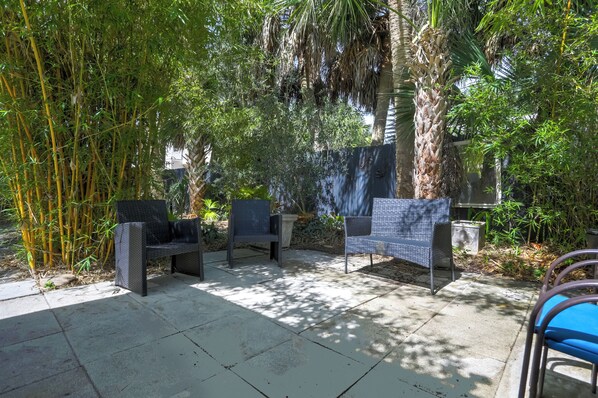 Un'area patio esterna con due sedie, un tavolo e una grande pianta di bambù.