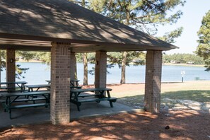 A covered picnic area with benches and a view of a lake. - Lakefront home in a Gated Community, 10 miles from Pinehurst Village (Seven Lakes)