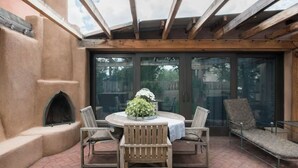 A patio with a round table and four chairs, a small plant on the table, and a fireplace.