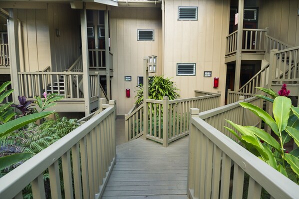 Una terraza de madera con barandillas que conduce a un edificio con varios balcones y escaleras.