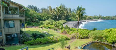 A hotel with a pool, a lawn, and a view of the ocean.
